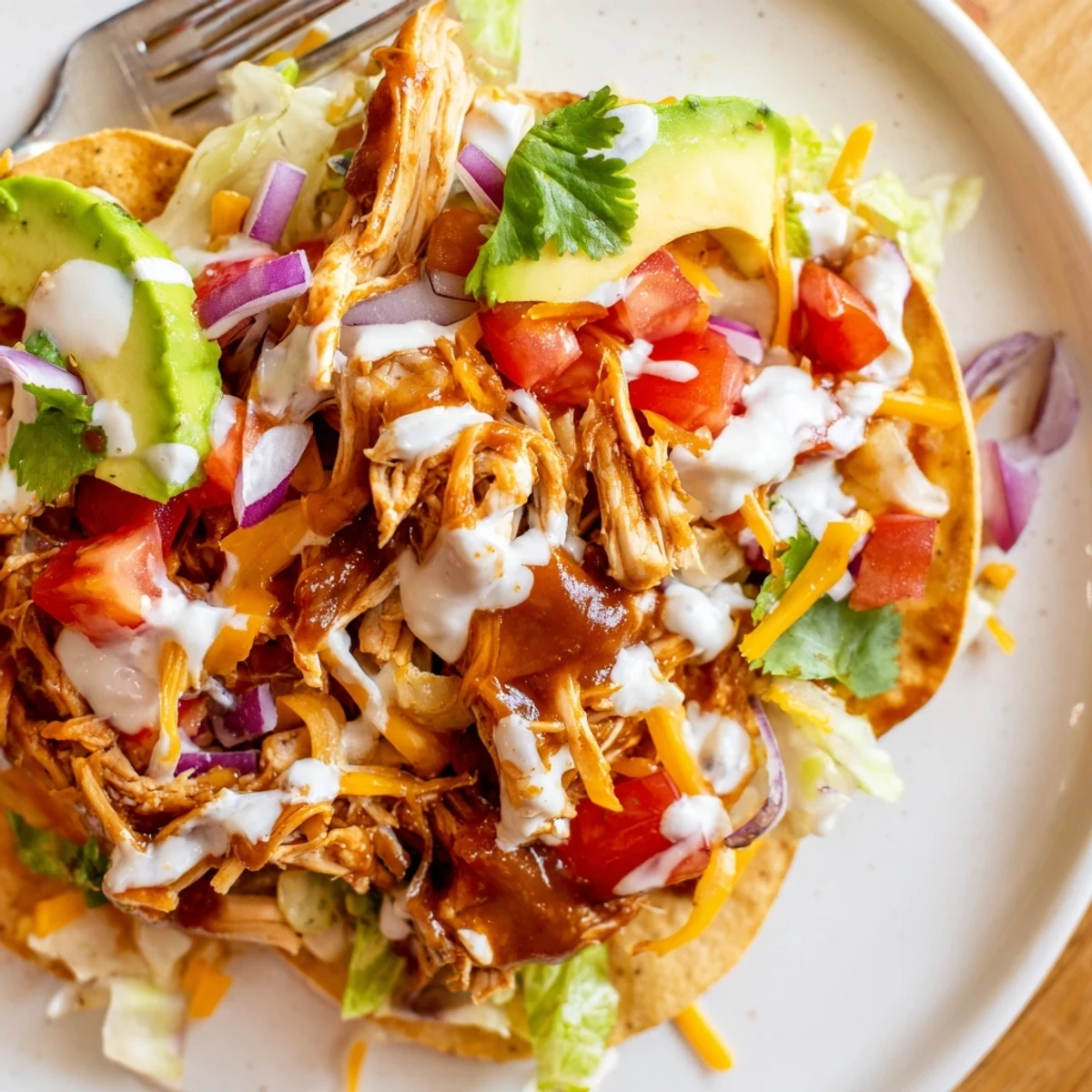 Golden corn tostada shells loaded with tender sweet smoky BBQ chicken and melted cheddar cheese drizzle