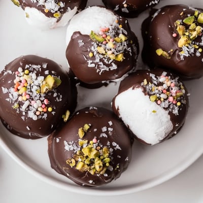 A close-up of Chocolate Dipped Marshmallows with a glossy dark chocolate shell and a sprinkle of flaky sea salt.