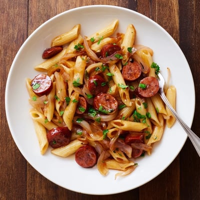 One-pan honey garlic sausage pasta dish with tender penne noodles tossed in savory sweet red glaze