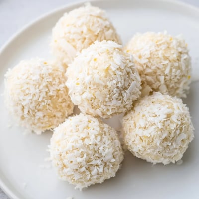 Freshly rolled citrus energy bites arranged on a wooden board with orange zest garnish
