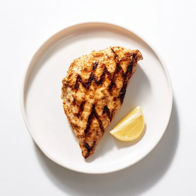 Savory sweet Maple Dijon Grilled Chicken slices arranged on a rustic wooden board with lemon wedges